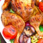 Tender grilled whole chicken served on a platter with herbs